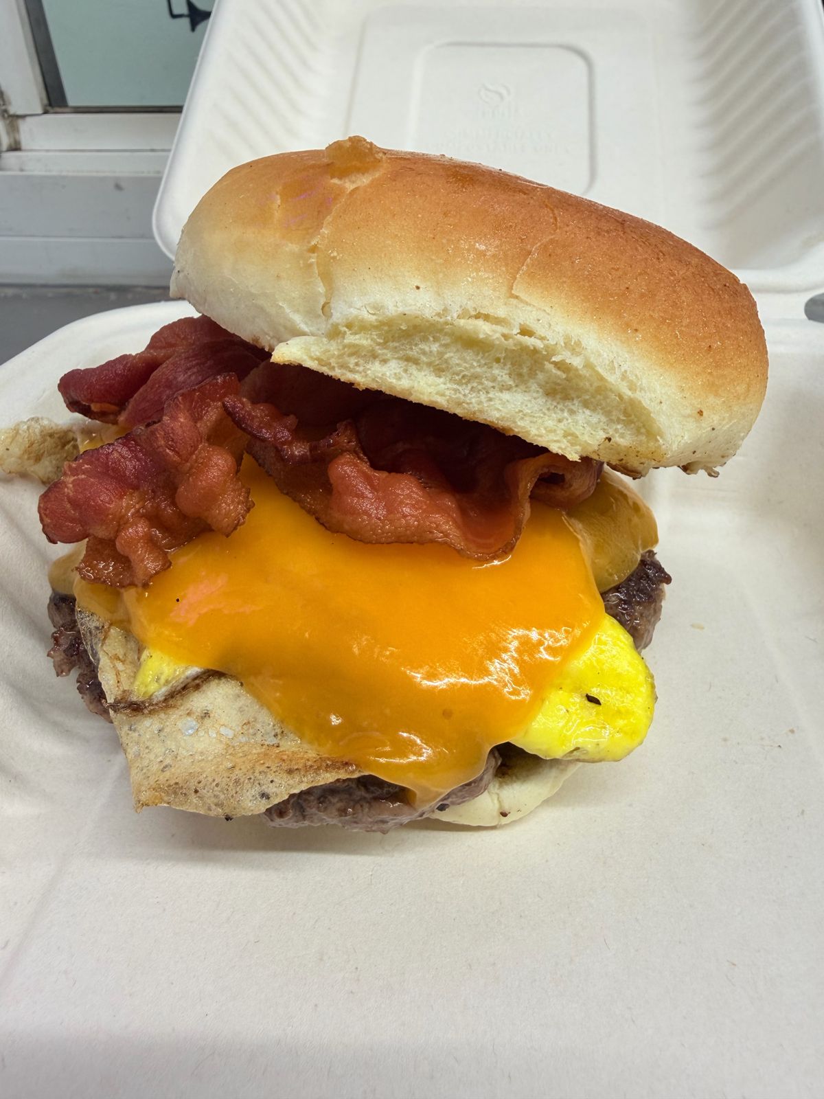 Bacon, egg and cheese breakfast burger in a to-go box
