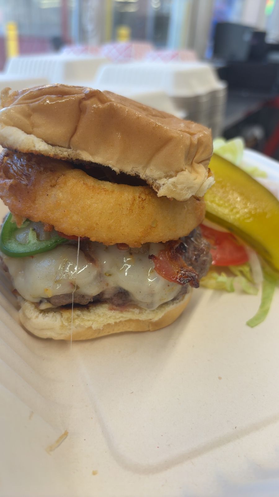 Burger stacked with an onion ring, jalapeños and bacon